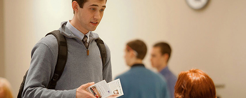 A student holding a program brochure at a career fair.